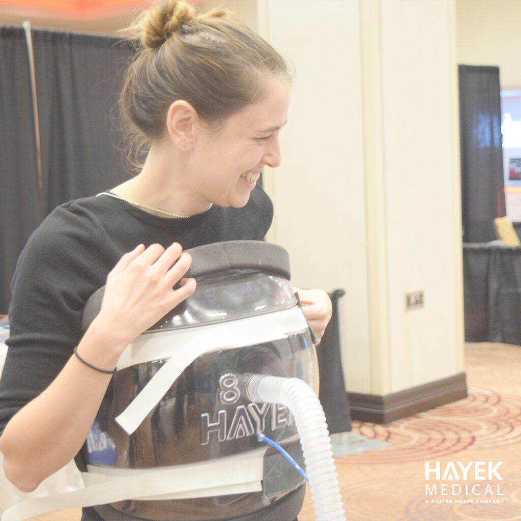 Smiling woman demonstrating Hayek BCV cuirass shell for non-invasive ventilation support